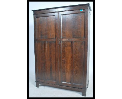 A 1920's oak bachelors compactum wardrobe. Raised on bracket feet with twin panel doors having a haberdashery lined appointed