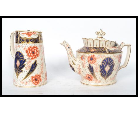 A 19th century Staffordshire teapot in the Imari pattern having a hinged ceramic lid atop together with the matching water ju