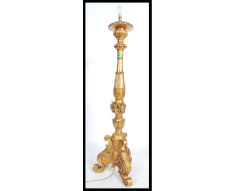 A large ornate gilt standard lamp raised on moulded tripod legs with gadrooning and acanthus leaf decoration with putti masks
