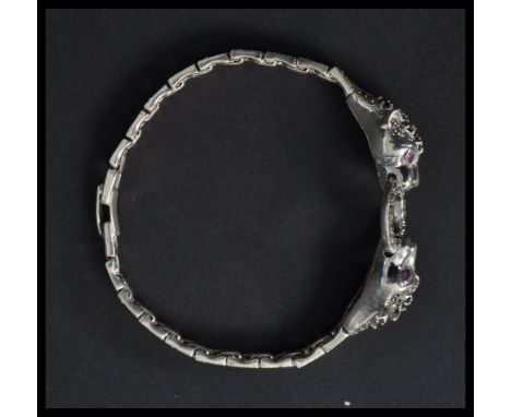 A sterling silver bracelet in the form of two panthers holding a ring with marcasite bodies and ruby set eyes. Weighs 25.4 gr