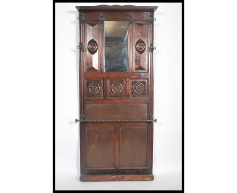 An early 20th century Edwardian oak wall mounted hall stand, having bevelled mirror inset, panel back, wrought Iron coat hook