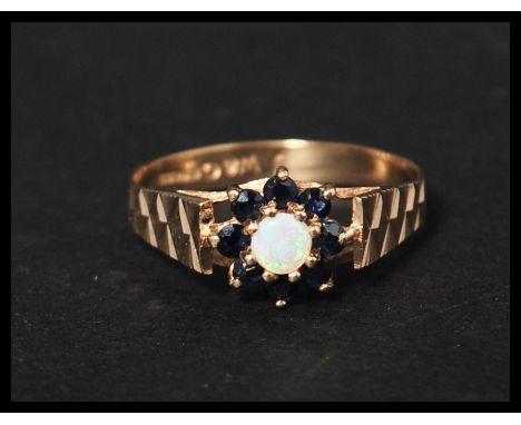 a hallmarked 9ct gold blue sapphire and opal ring set with a central opal surrounded by a sapphire halo having star cut shoul