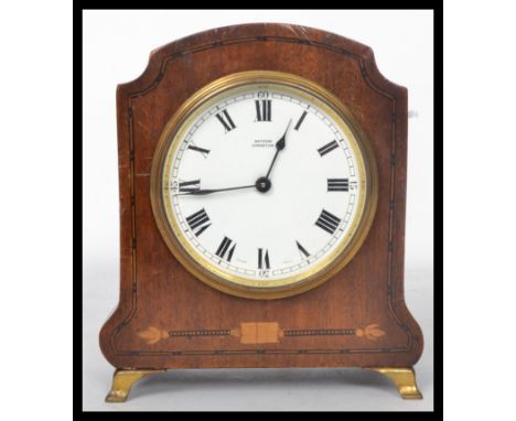 An early 20th century Edwardian mahogany mantel clock having box wood inlay. The white enamel dial having faceted hands. The 