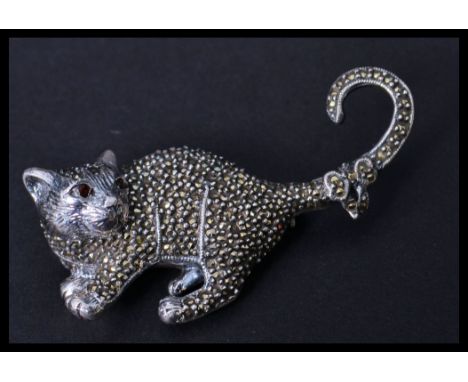 A sterling silver and marcasite brooch in the form of a cat with ruby eye. Pin to verso. Weighs 18.6 grams.