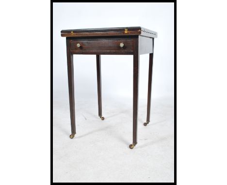 An Edwardian mahogany envelope card - games table being raised on square tapering legs with brown ceramic castors. Above a fi
