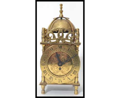 A Smiths Brass eight day XVII Century style lantern clock, bell with finial over a circular dial, Roman numerals, turned feet