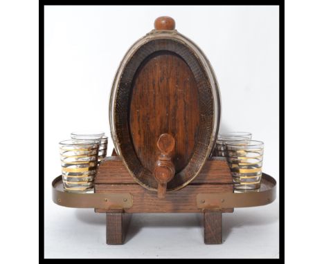 An early 20th century spirit decanter dispense in the form of a novelty spirit coopered barrel with a set of six banded drink