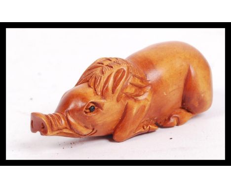 A 20th century carved Japanese netsuke in the form of a seated pig.