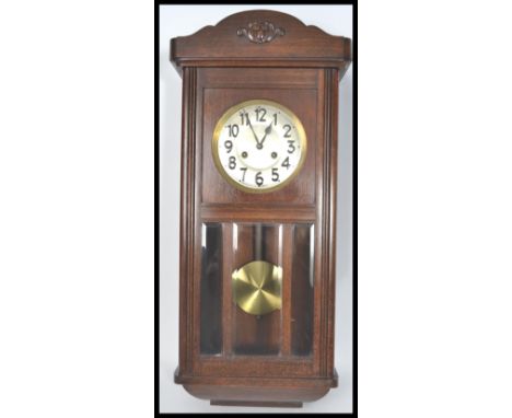 An early 20th century oak cased wall clock. The silvered dial having faceted hands with carved floral spray to top. Measures 