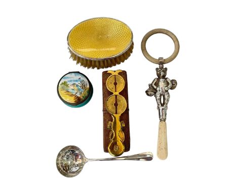 Silver child's rattle, silver and enamel brush, enamel box, silver sifting spoon and sovereign scales.