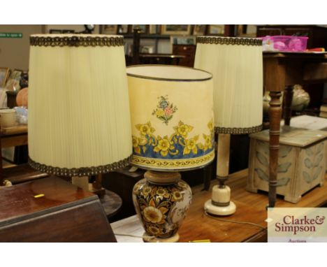 A floral decorated pottery table lamp and shade; and a pair of onyx table lamps and shades 