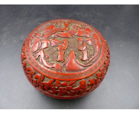 A CHINESE CINNABAR LACQUER BUN SHAPED BOX, THE COVER WORKED WITH A ROUNDEL OF TWO SAGES BELOW AND WILLOW TREE IN A MOUNTAIN R