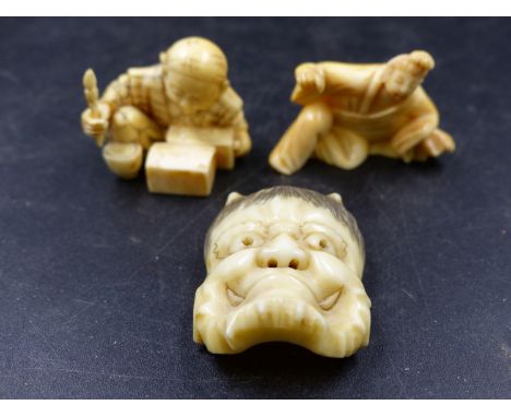 AN ONI NOH IVORY MASK.   3.5cms A MARINE IVORY OKIMONO OF A CRAFTSMAN PAINTING BOXES.   W.3.5cms AND A MARINE IVORY NETSUKE C