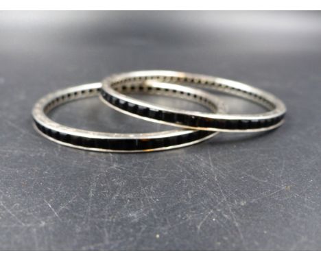 A PAIR OF WHITE GOLD ART DECO GEMSET BANGLES, HAND SET AND BORDER ENGRAVED WITH A SCROLL DESIGN. 