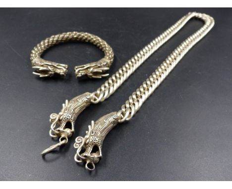 A WHITE METAL ORIENTAL CURB NECKLACE WITH DRAGON HEAD DECORATED CLASPS AND A SIMILAR BANGLE. 