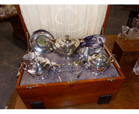 AN ART DECO WALNUT CASED SILVER PLATED TEA SET, THE INTERIOR WITH RISING ACTION AND MUSICAL MOVEMENT.   51 x 28 x 33cms.