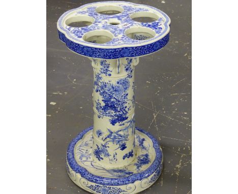 A JAPANESE BLUE AND WHITE PORCELAIN STICK STAND, THE PETAL SHAPED TOP PIERCED WITH FIVE CIRCULAR HOLES, THE COLUMN AND DISHED