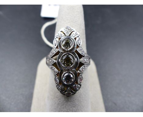 A WHITE METAL DIAMOND SET ELONGATED RING, STAMPED 750. THE THREE CENTRAL DIAMONDS ARE ENCASED IN INDIVIDUAL RUB OVER SETTINGS