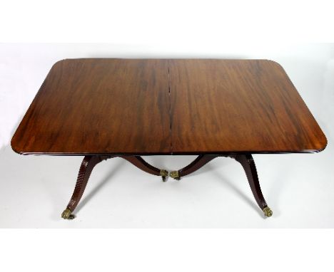 A mahogany two-pillar dining table, the top in two sections with rounded ends and reeded edges, on two turned and reeded trip