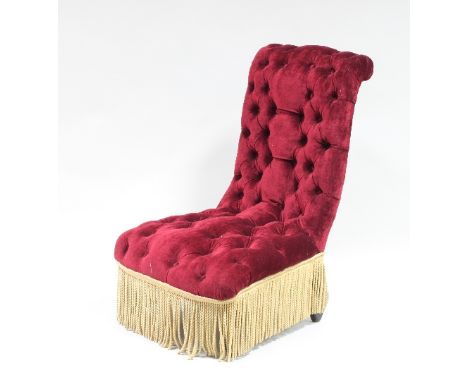 A Victorian button back nursing chair with red velvet upholstery and tasselled fringing and a contemporary beige loose cover