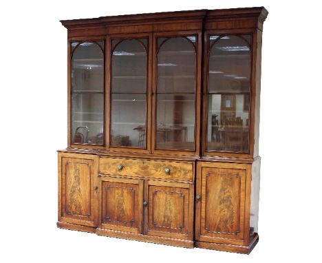 A fine Regency mahogany breakfront library bookcase, with moulded cornice, fitted adjustable shelves enclosed by four arch to