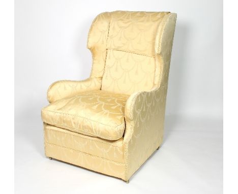 A wingback armchair with loose seat cushion, upholstered in patterned gold satin fabric