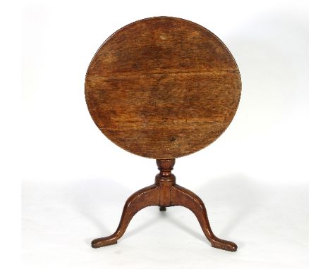 A George III oak table on a turned column and tripod support, the tip-up-top 67cm diameter