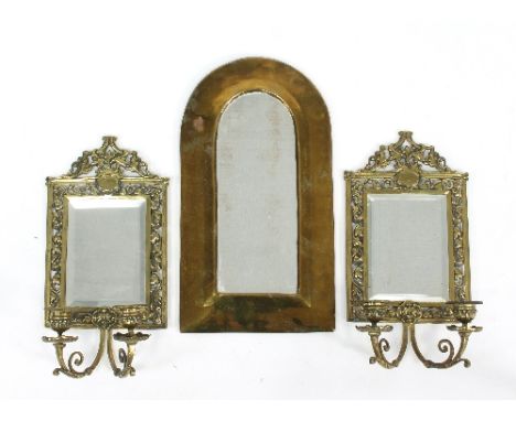 A pair of brass wall mirrors with two candelabra to the base and a brass arch top mirror