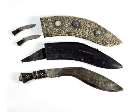 A kukri with horn handle and lion mask to the pommel, with leather scabbard and outer white metal scabbard with embossed deco