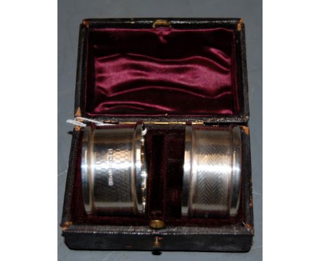 A pair of George V silver napkin rings, having engine turned decoration, in fitted leather case 