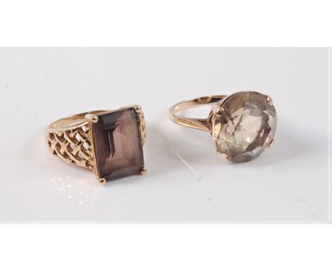 A 9ct smokey quartz ring, the step cut rectangular smokey squartz, claw mounted with fretwork tapered shoulders and plain ban