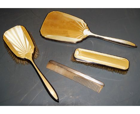 An Art Deco silver and guilloche yellow enamel backed four-piece dressing table set
