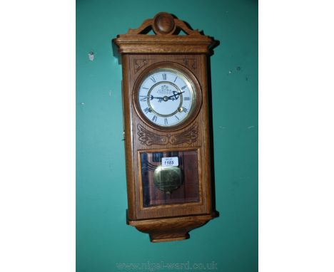 An American style Wall Clock, Oak cased with pierced, fret cut pediment, long carved door with upper circular pane, brass and