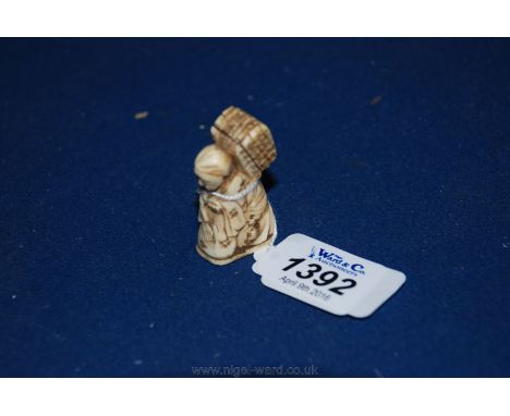 A small early Meiji period Netsuke of kneeling figure with backpack.