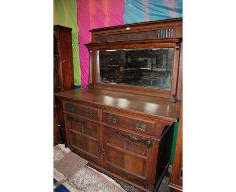 An arts and crafts Oak mirror back Sideboard, having moulded cornice over carved and fret-cut rear panel, over shaped and mou