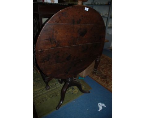 A Georgian Oak tilt top Occasional Table having four plank circular top,  on turned pedestal with urn and ring detail, on thr