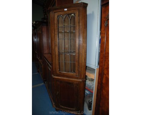 A circa 1900 Oak floor standing two tier Corner Cabinet, with moulded cornice over the upper nineteen pane leaded glazed door