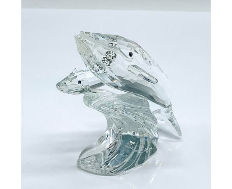 Multifaceted clear crystal whale, mother and child, each with black eyes riding a clear wave. Part of the Mother and Child Se