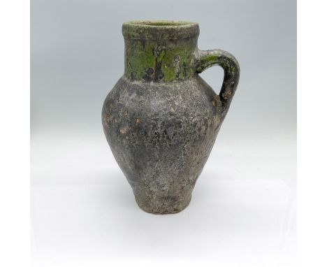 A pitcher in a black and green glaze. Dimensions: 7.25"L x 6.75"W x 10.5"HCondition: Age related wear. As is. Several cracks 