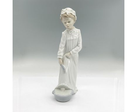 Glazed porcelain figure of a girl in a nightgown and nightcap getting ready for bed, washing her feet. Nao backstamp. Dimensi