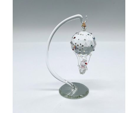 A whimsical figure of a passenger riding a hot air balloon adorned with colored rhinestones. This item has a stand included. 