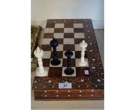 A decorative bone chess set, raised on a Persian style chess board. CONDITION REPORT: Black King - with chip to cross and top