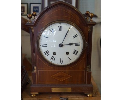 An Edwardian inlaid mahogany bracket clock with central enamel dial, raised on four gilt ball feet.