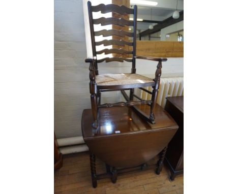 A oak drop leaf gate leg dining table together with a rush seated ladder back rocking chair.