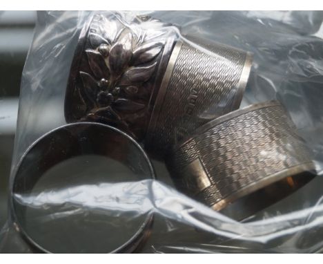 A good quality hallmarked silver napkin ring, having relief decoration together with a pair of engine turned examples.