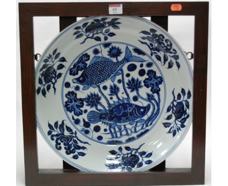 A large modern blue and white charger, decorated with koi carp, housed in a wooden surround 