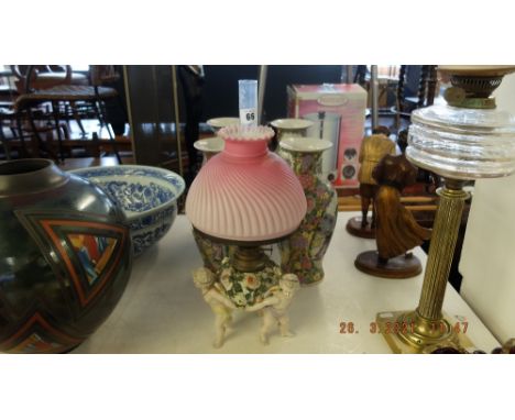 A Victorian Sitzendorf cherub oil lamp with matching satin shade and chimney