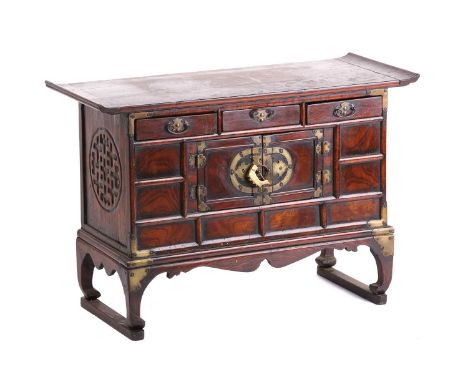 A Chinese elm low cabinet, the first half of the 20th century, with everted top above three frieze drawers and a pair of cupb