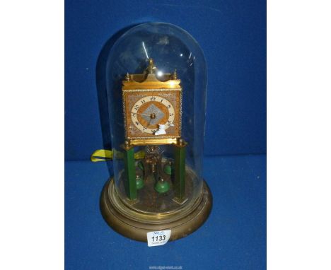 An Anniversary clock under a glass dome having Arabic numerals surrounding a patterned metal diamond shaped panel with simila