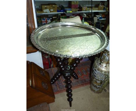 A Benares table with white metal engraved circular top fixed onto a bobbin tripod base, 23'' diameter x 27 1/2'' high.